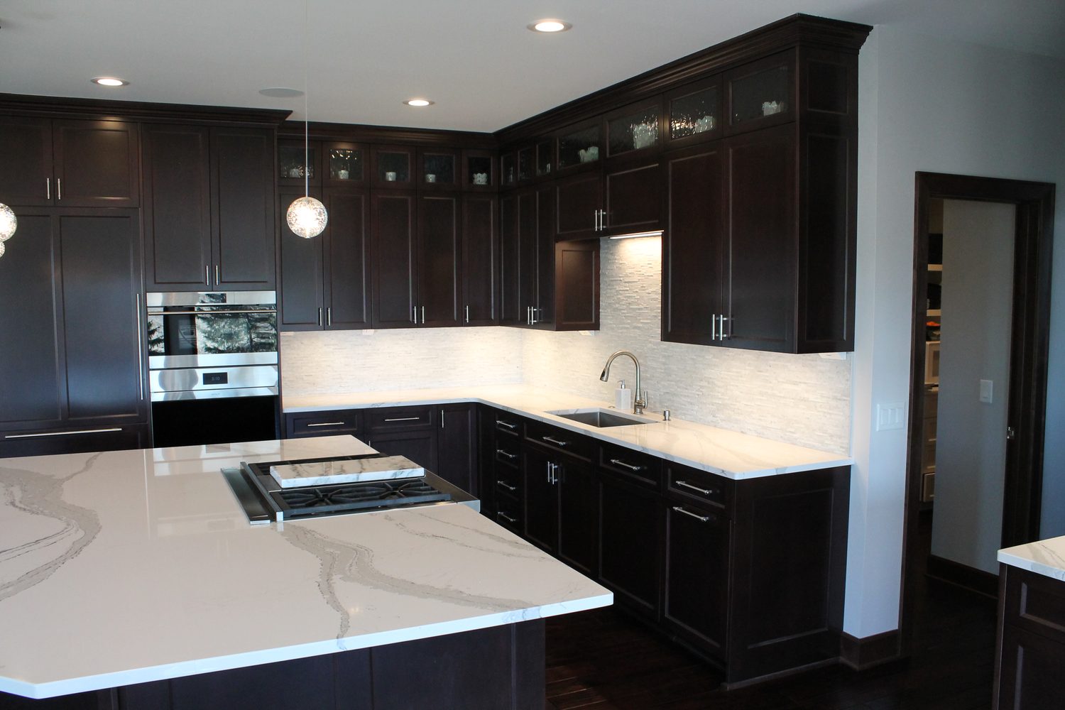 Espresso cabinetry and white quartz waterfall island in a Waconia custom kitchen by ACE Design Build