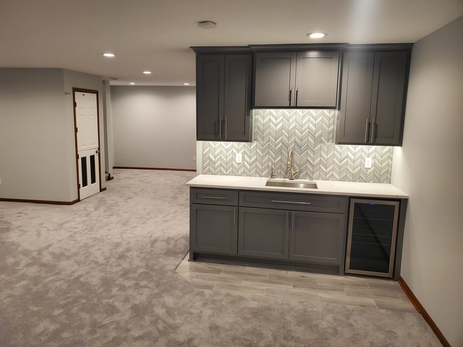 Custom wet bar with cabinetry and stone backsplash