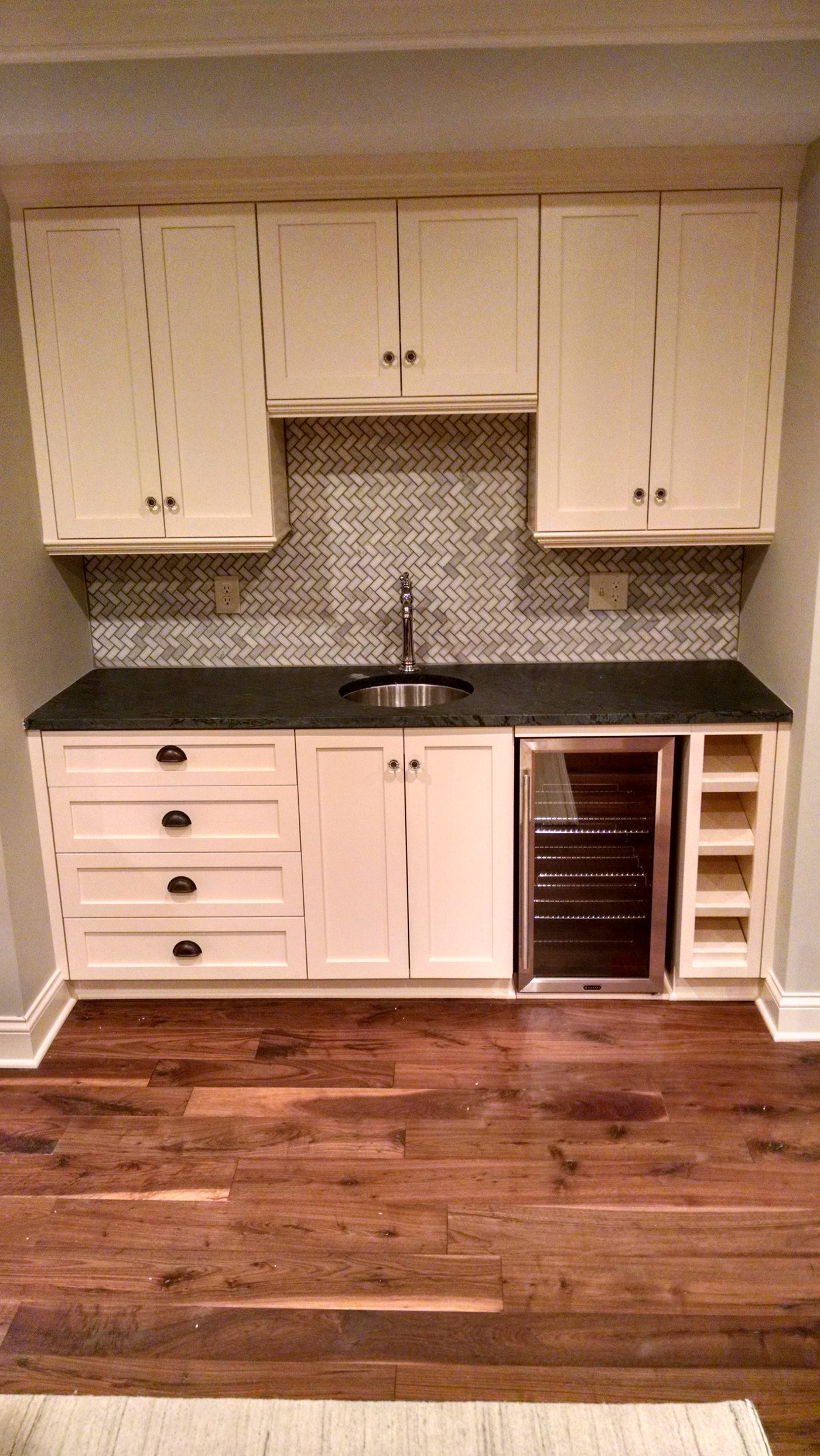 Custom basement bar with cabinetry and granite island in Victoria